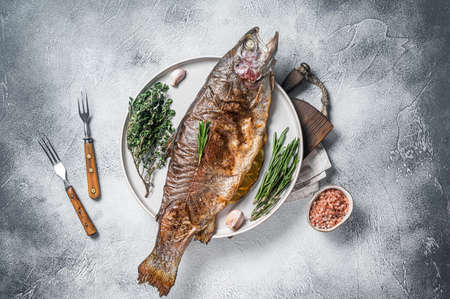 Baked silver trout, roasted fish on a plate with herbs. white background. top view.の写真素材