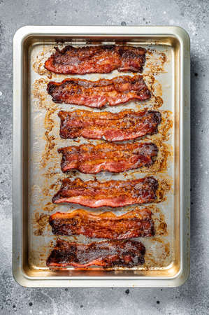 Strips of fried bacon in baking dish. Gray background. Top viewの写真素材