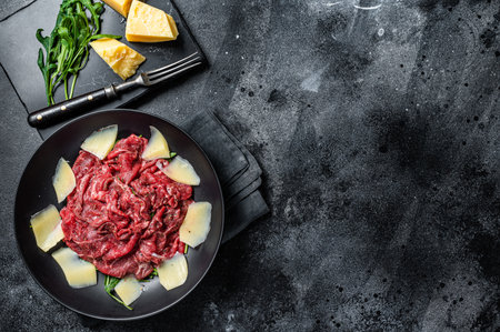 Carpaccio salad with marbled beef meat, arugula and Parmesan. Black background. Top view. Copy spaceの写真素材