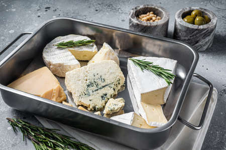 Different sorts of cheese - camembert, brie, blue cheese, parmesan with olives, nuts and herbs. gray background. top view.の写真素材