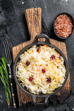 Sauerkraut in a skillet with black pepper and cranberry, Fermented cabbage. Black background. top view.の写真素材