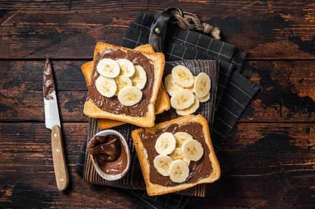 Toasts bread with bananas and chocolate cream on wooden board. wooden background. top view.の写真素材
