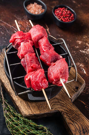 Lamb shish kebab, Raw meat Skewers with herbs on grill. dark background. top view.