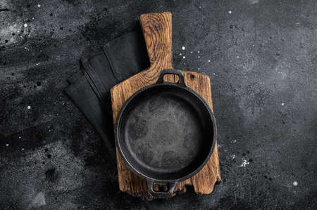 Cooking background with Empty cast-iron skillet on rustic towel. Black background. top view. copyspace.の写真素材