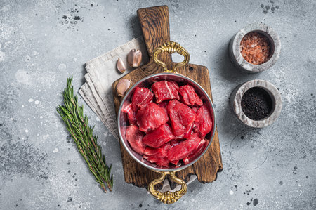 Uncooked Raw diced beef veal meat for stew in skillet. Gray background. Top view