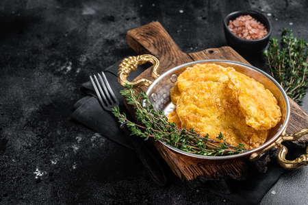 Fried Hash brown potato, hashbrown in a skillet. Black background. top view. copyspace.