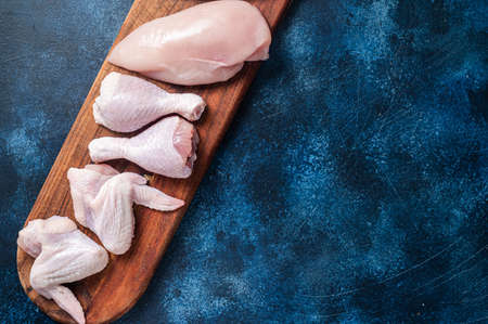 Chicken meat assortment. Raw parts - drumstick, breast fillet, wings, thigh. blue background. top view. copyspace.の写真素材