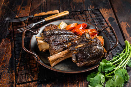 Homemade Braised Lamb Shanks with Sauce and Herbs in a steel tray. wooden background. top view.の写真素材