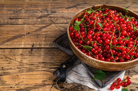 Ripe Red currant berries in a wooden plate. wooden background. top view. copyspace.の写真素材