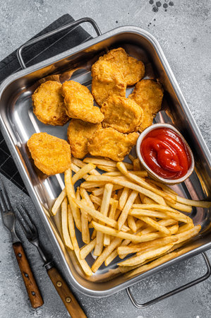 Fried crispy chicken nuggets with ketchup and French fries. gray background. top view.