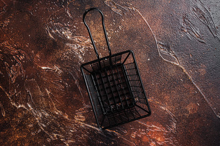 Empty iron frying basket on rustic table. dark background. top view. copyspace.