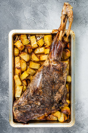 Roast lamb mutton leg with potatoes and rosemary in baking dish. white background. top view.の写真素材