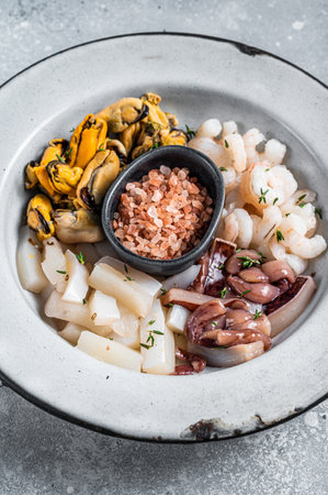 Raw seafood mix in a rustic plate. gray background. top view.