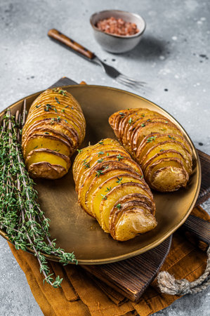 Baked Hasselback Potato with Fresh thyme and rosemary. gray background. top view.