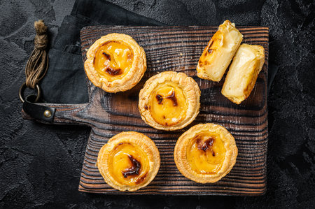 Custard Tarts Pasteis de Belem, Portuguese pastel de Nata. Black background. top view.