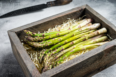 Raw green asparagus in a wooden box. white background. top view.の写真素材