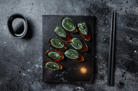 Chinese Century eggs, black egg is cut showing dark yolk. Black background. top view.の写真素材
