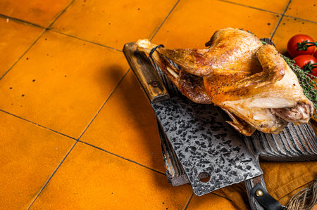 Grilled guinea fowl with herbs and spices on butcher board, cooked game bird. orange background. top view. copyspace.の写真素材