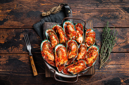 Delicious seafood mussels cooked in tomato sauce with garlic, herbs. wooden background. top view.の写真素材