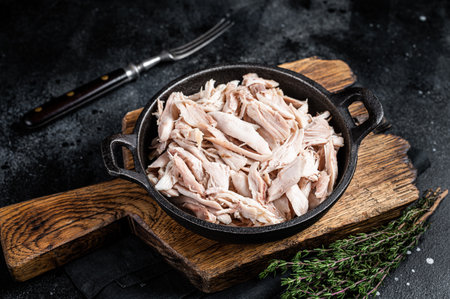 Sliced Pieces of chicken meat in a skillet, pulled chicken. Black background. top view.の写真素材