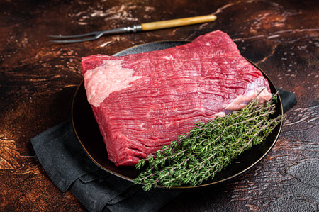 Fresh beef brisket, raw meat with herbs. dark background. top view.
