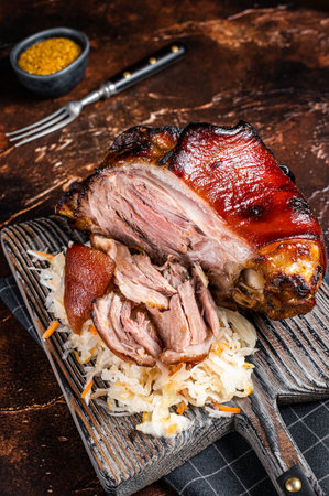 Schweinshaxe Roasted Pork Ham Hock, knuckle with Sauerkraut served on a wooden board. dark background.の写真素材