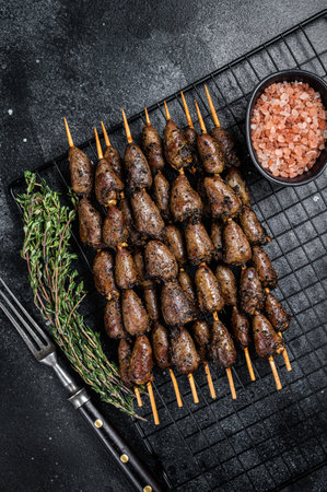 Grilled shish kebab with chicken hearts on a grill. Black background. top view.の写真素材