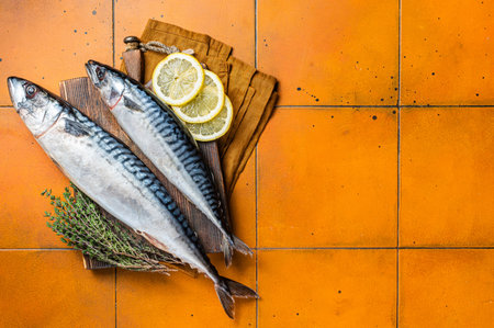Raw mackerel fish, Scombrus with herbs and spices on wooden board. orange background. top view.