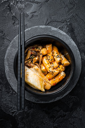 Korean street food Tteokbokki, Topokki fried rice cake stick in spicy sauce. Black background. top view.の写真素材