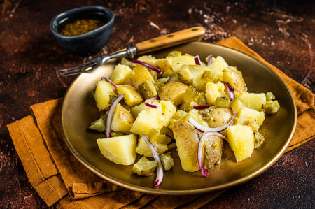 Warm Potato salad with red onion, capers, greens in a plate. dark background. top view.の写真素材