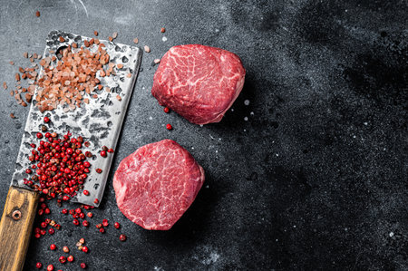 Raw steaks fillet Mignon on a butcher cleaver. beef tenderloin. Black background. top view. Space for text.の写真素材