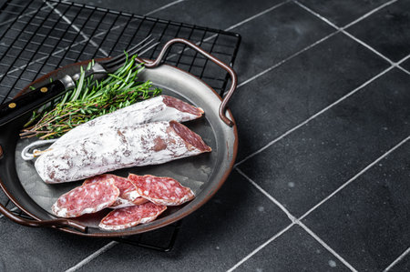 Fuet Salami slices in a steel tray. Traditional Spanish sausage. Black background. top view. copyspace.の写真素材