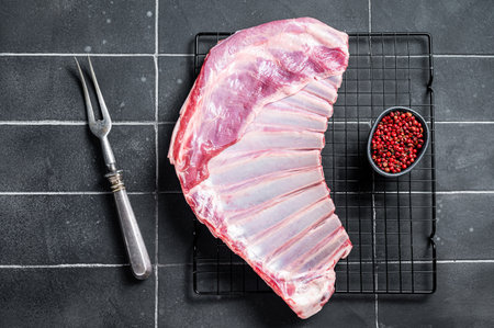 Rack of lamb, raw mutton ribs on kitchen table with spices. Black background. top view.の写真素材