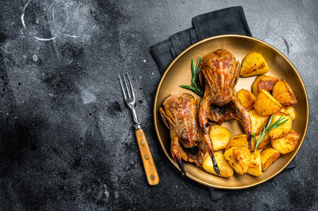 Delicious roasted quails with herbs in a plate with fried potato. Black background. top view. copyspace.の写真素材