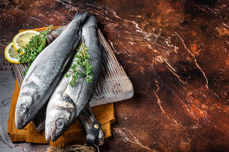 Raw Sea Bass, Branzino fish with thyme and lemon. dark background. top view. copyspace.の写真素材