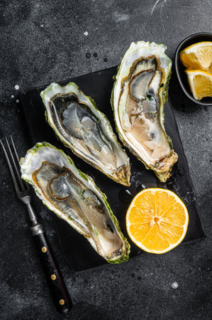 Seafood Brassiere, open Oysters with lemon. Black background. top view.の写真素材