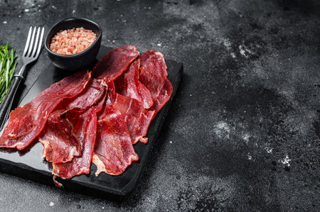 Turkish sliced pastrami (kayseri pastirma), dried beef meat with spices on marble board. Black background. top view. copyspace.の写真素材