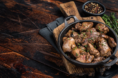 Roasted chicken liver with onions in a skillet. wooden background. top view. copyspace.の写真素材