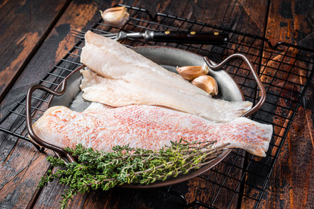 Raw red perch fillet, redfish fish meat in a steel tray. wooden background. top view.