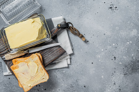 Slices of toast bread with butter on wooden board. gray background. top view. copyspace.の写真素材