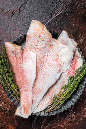 Raw ocean red perch fillet, Snapper fish with herbs. Dark background. Top viewの写真素材