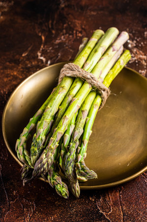 Bunch of Organic green asparagus in a plate. dark background. top view.の写真素材