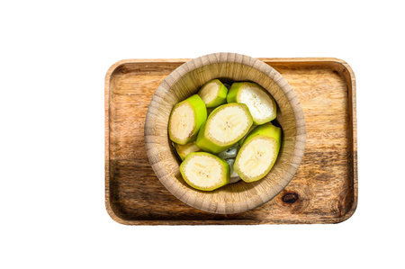 Sliced green banana in a wooden bowl. isolated on white backgroundの写真素材
