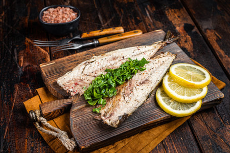 Delicious baked mackerel fillets with greens, garlic and lemon on wooden board. wooden background....