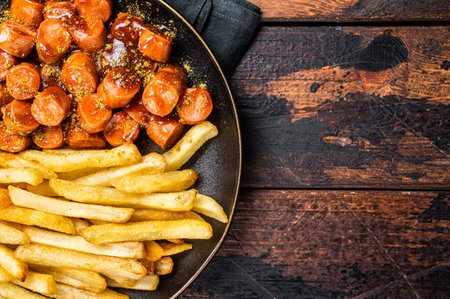 German currywurst meal, curry wurst with French fry served in a plate. Wooden background. Top view.の写真素材
