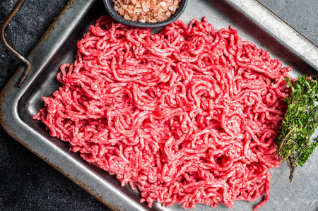 Unccoked Mince Ground meat, raw mincemeat beef and pork in a kitchen tray. Black background. Top viewの写真素材