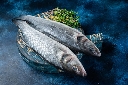 Uncooked Raw Sea Bass fish, Seabass with thyme. blue background. top view.
