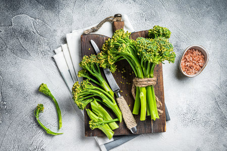 Fresh bunch of Broccolini sprouts on cutting board ready for cookining. White background. Top view