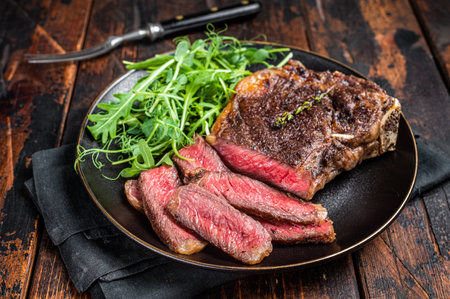 BBQ Grilled Wagyu New York beef meat steak or Striploin steak in a plate with salad. Wooden background. Top view.の写真素材