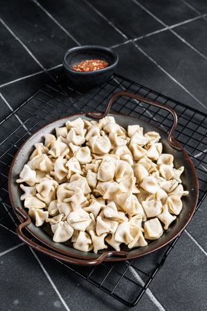 Cooking Manti Dumpling, raw food in a steel tray. Black background. Top view.の写真素材